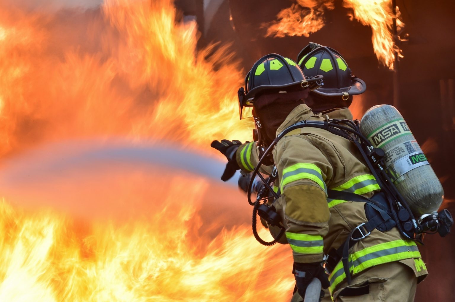 Firefighters tackling a fire with hose pipe