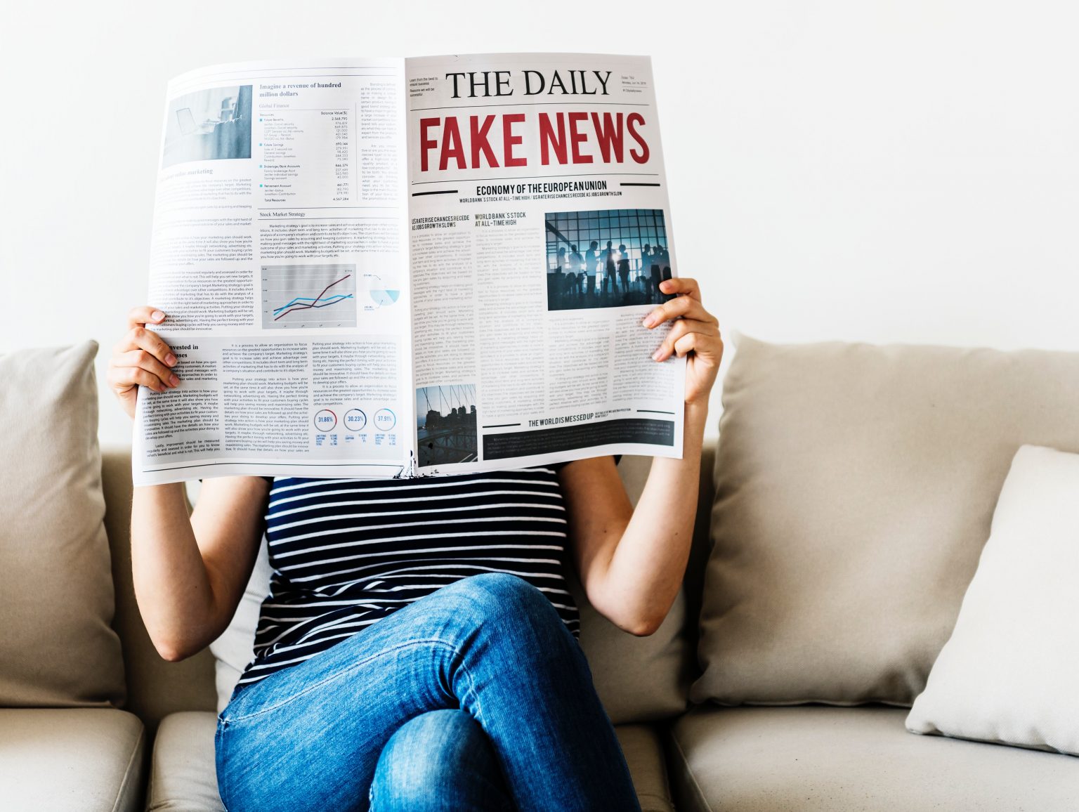 women reading a newspaper that states 'fake news' in re text