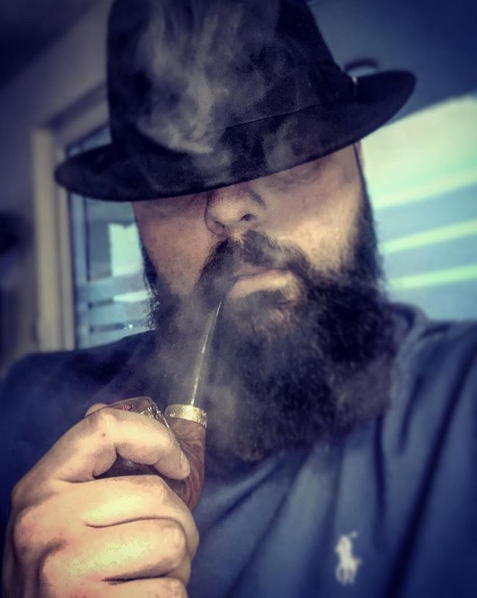 Kapka's Flava in a trilby hat puffing on a pipe