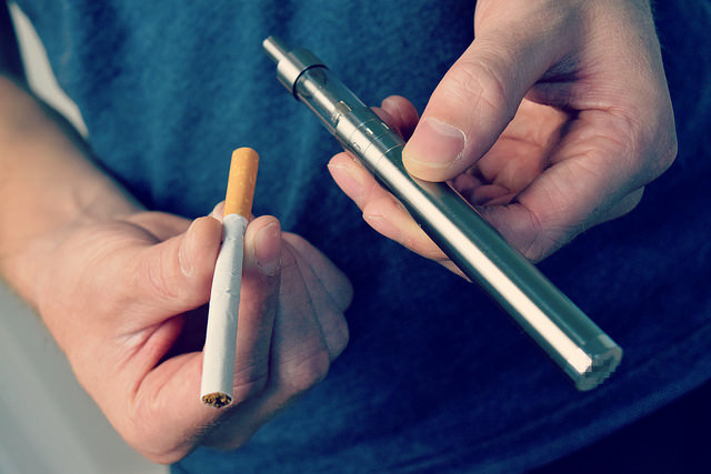 a man comparing a cigarette with a vape device