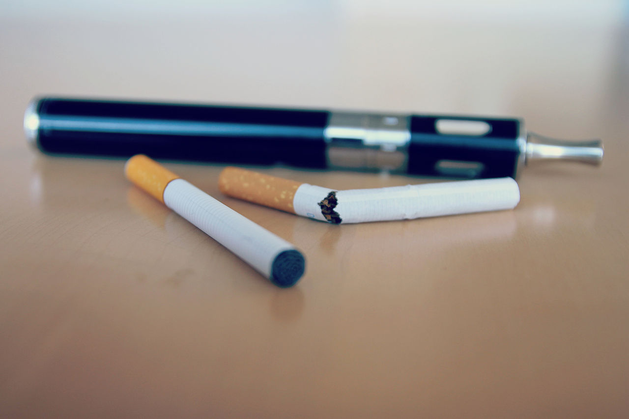 cigarettes and vape pen on a brown table