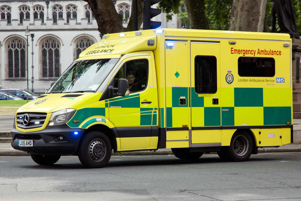 yellow and green london ambulance van driving to an emergency