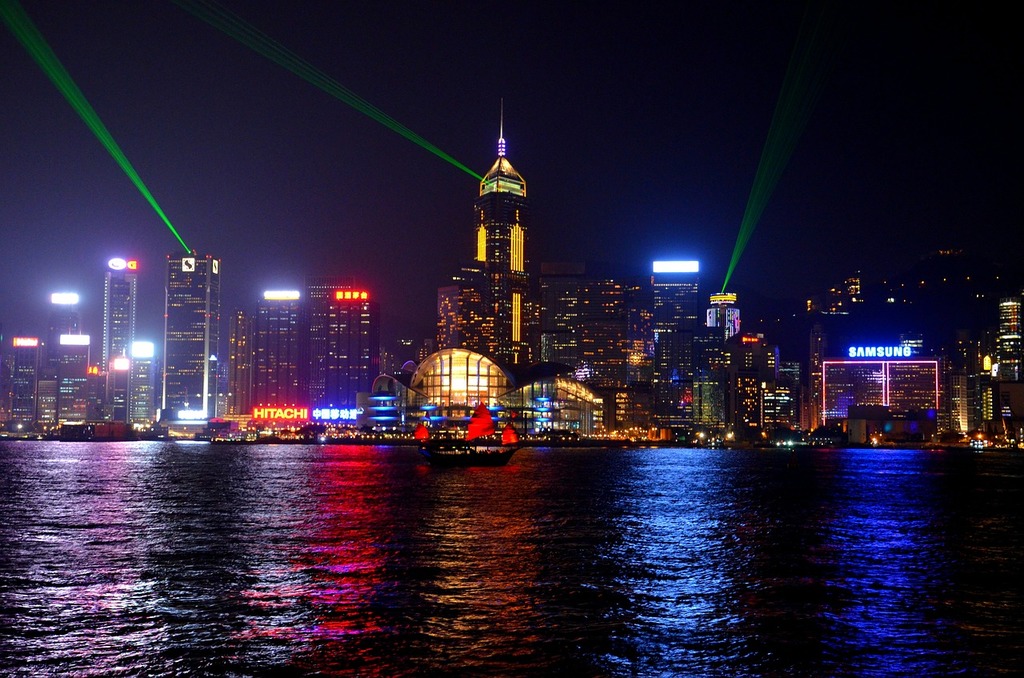 Hong Kong skyline at night with green lights beaming across the harbour