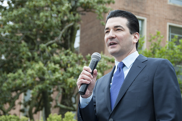 a man in a suit speaking into a microphone at a rally