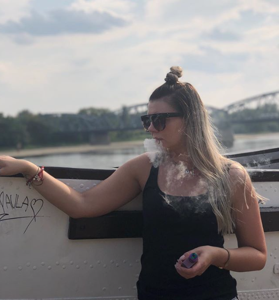 Milly Moon vaping alongside a river and a bridge