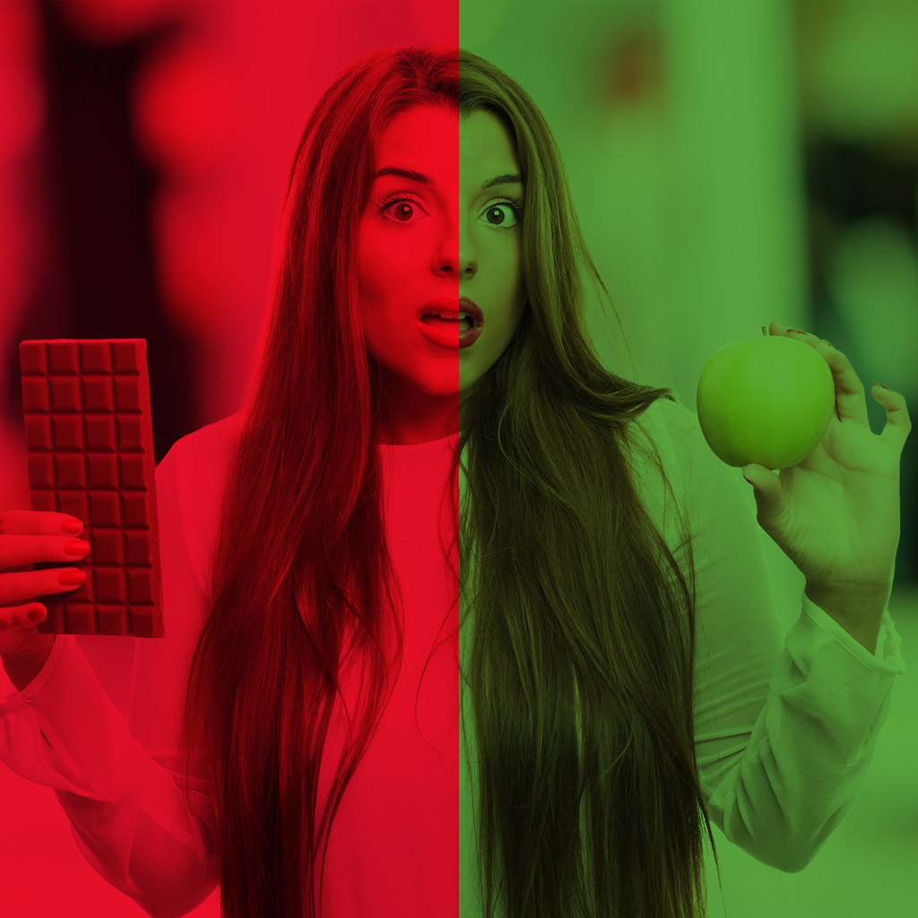 unhealthy v healthy food - girl holding a chocolate bar and an apple