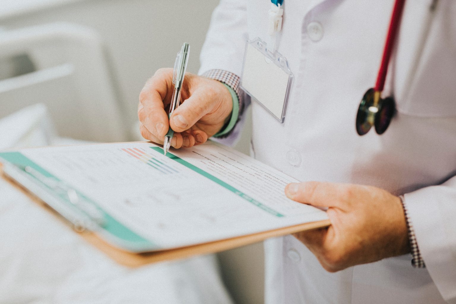 a doctor in a white jacket with a red stethoscope writing on a clipboard