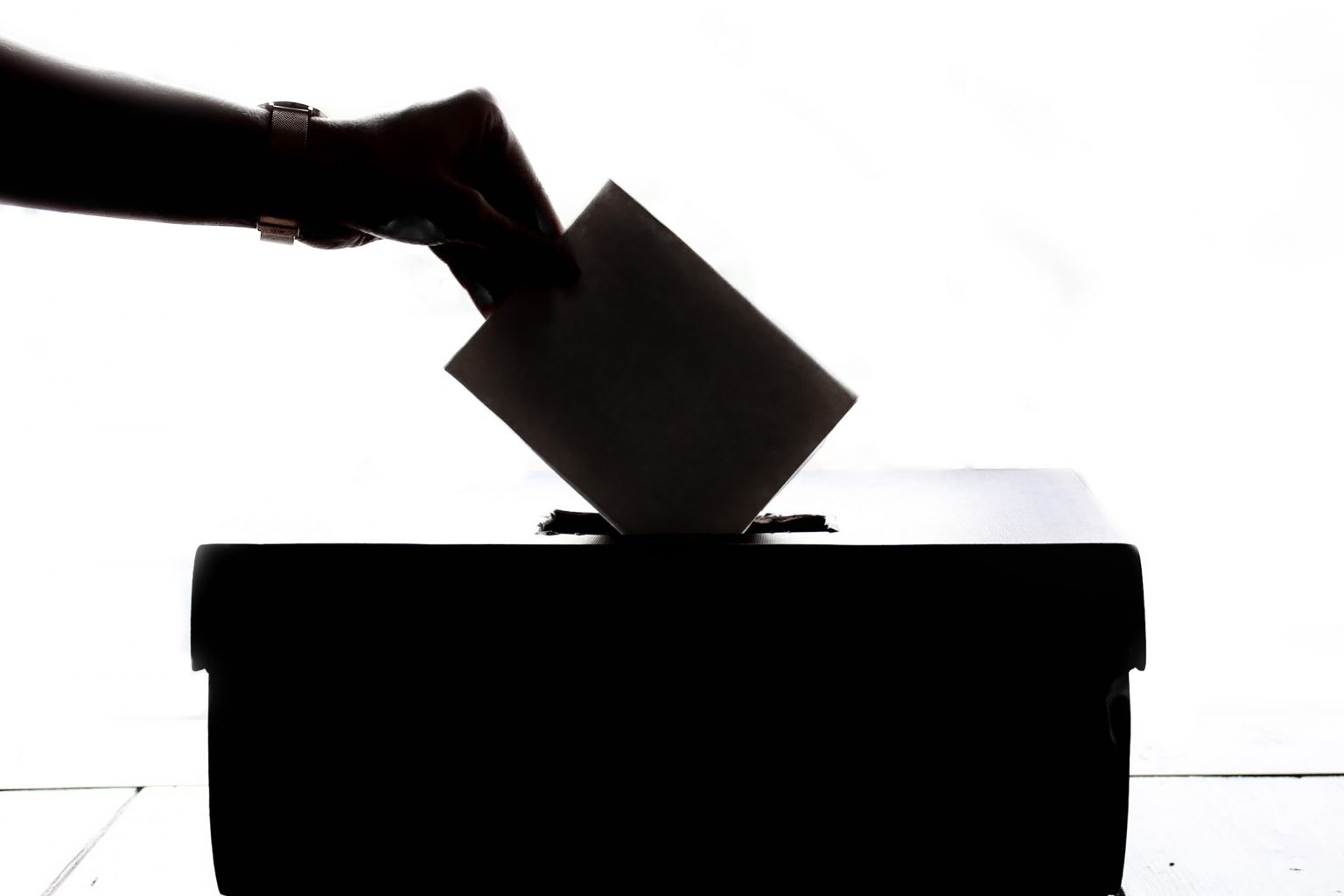 a woman posting her vote into a ballot box