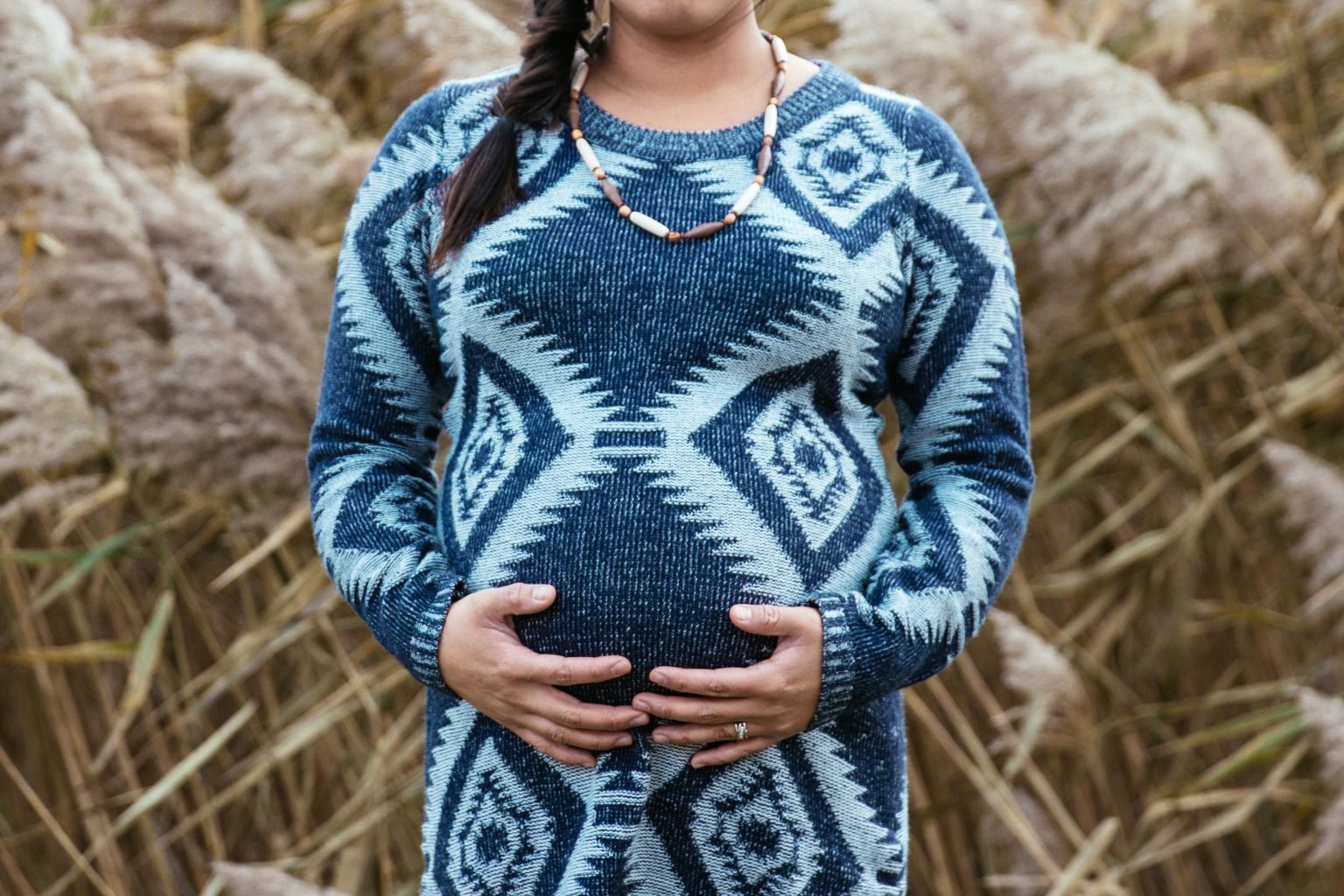 a pregnant woman in a blue fairisle dress posing in a field