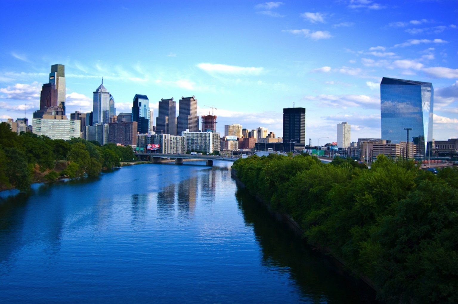 Philadelphia skyline with trees and a river in the forefront