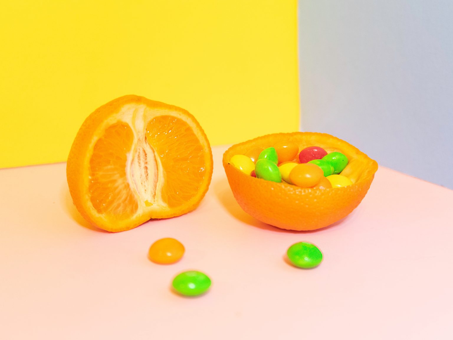 orange cut open with skittles inside