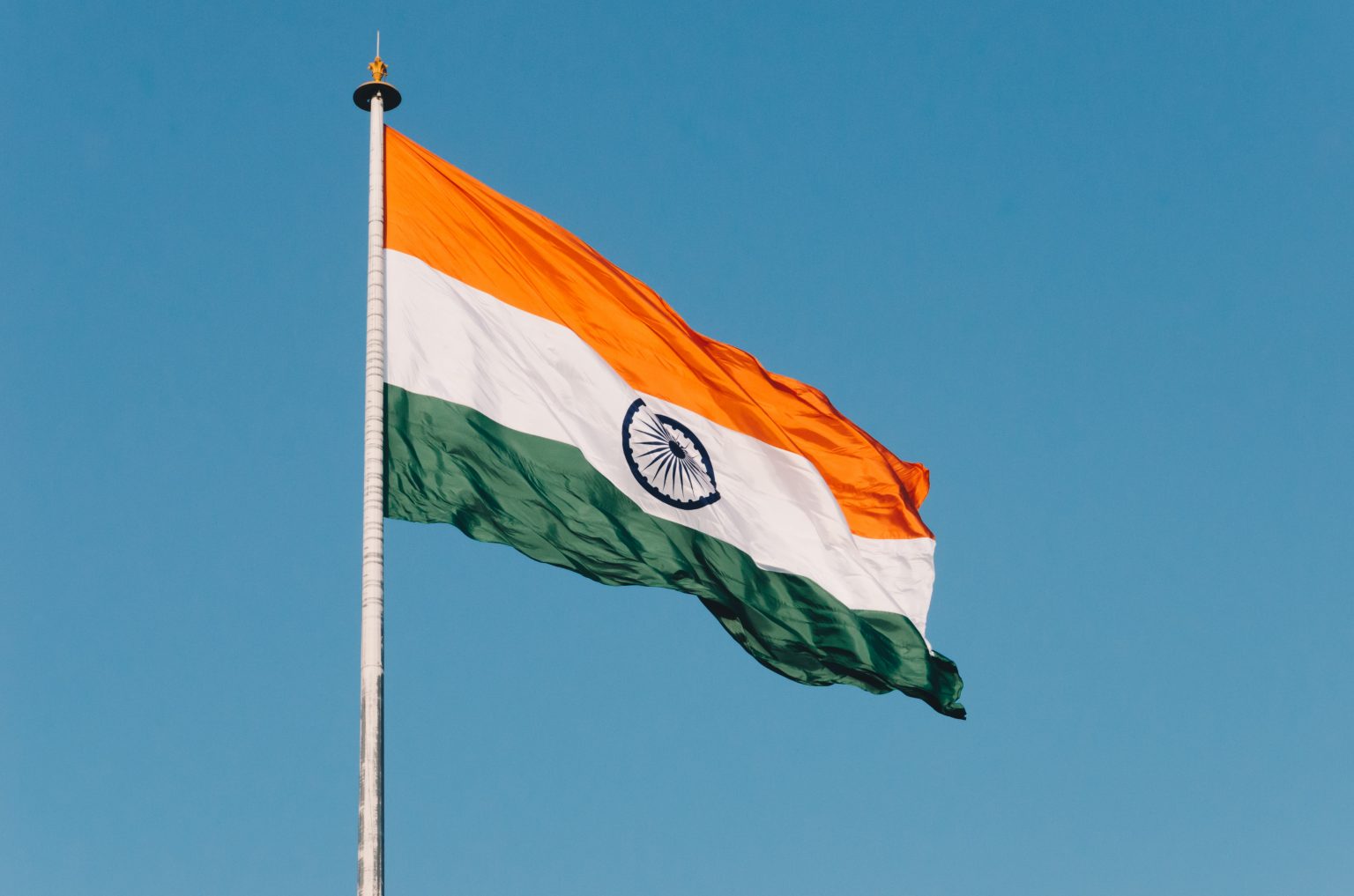 Indian flag flying in a breeze against a bright blue background