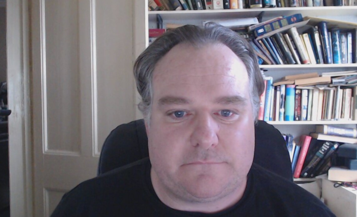 Shot of a man sitting with books behind him