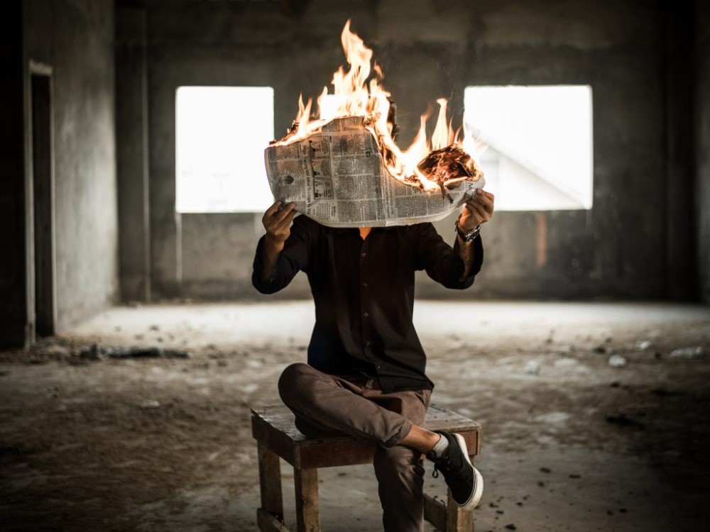 Man reading burning newspaper