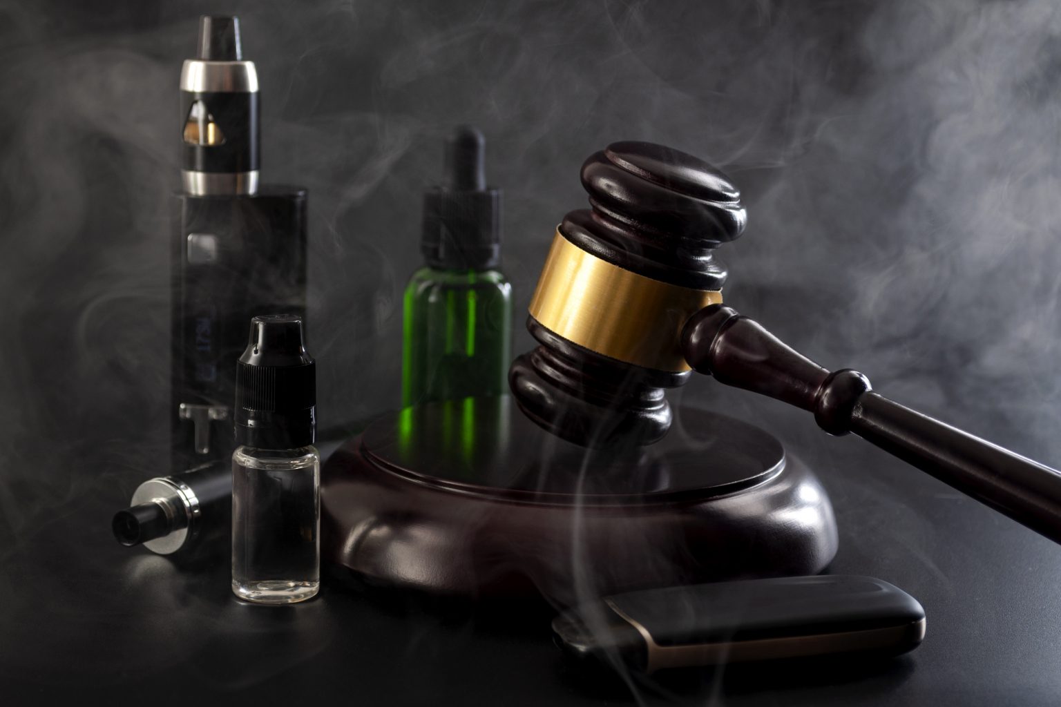 judges gavel surrounded by vape equipment