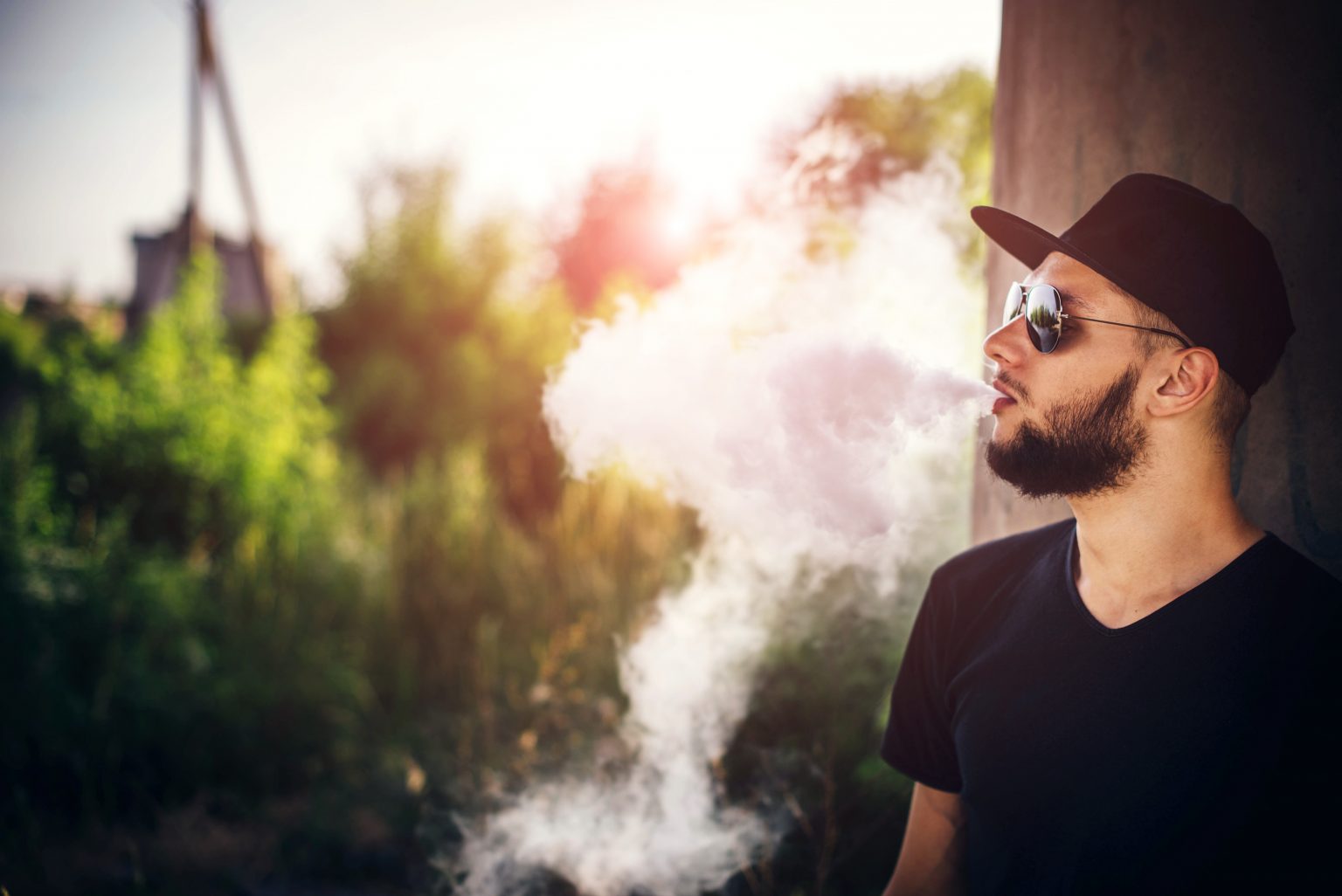 Man in sunglasses and cap vaping