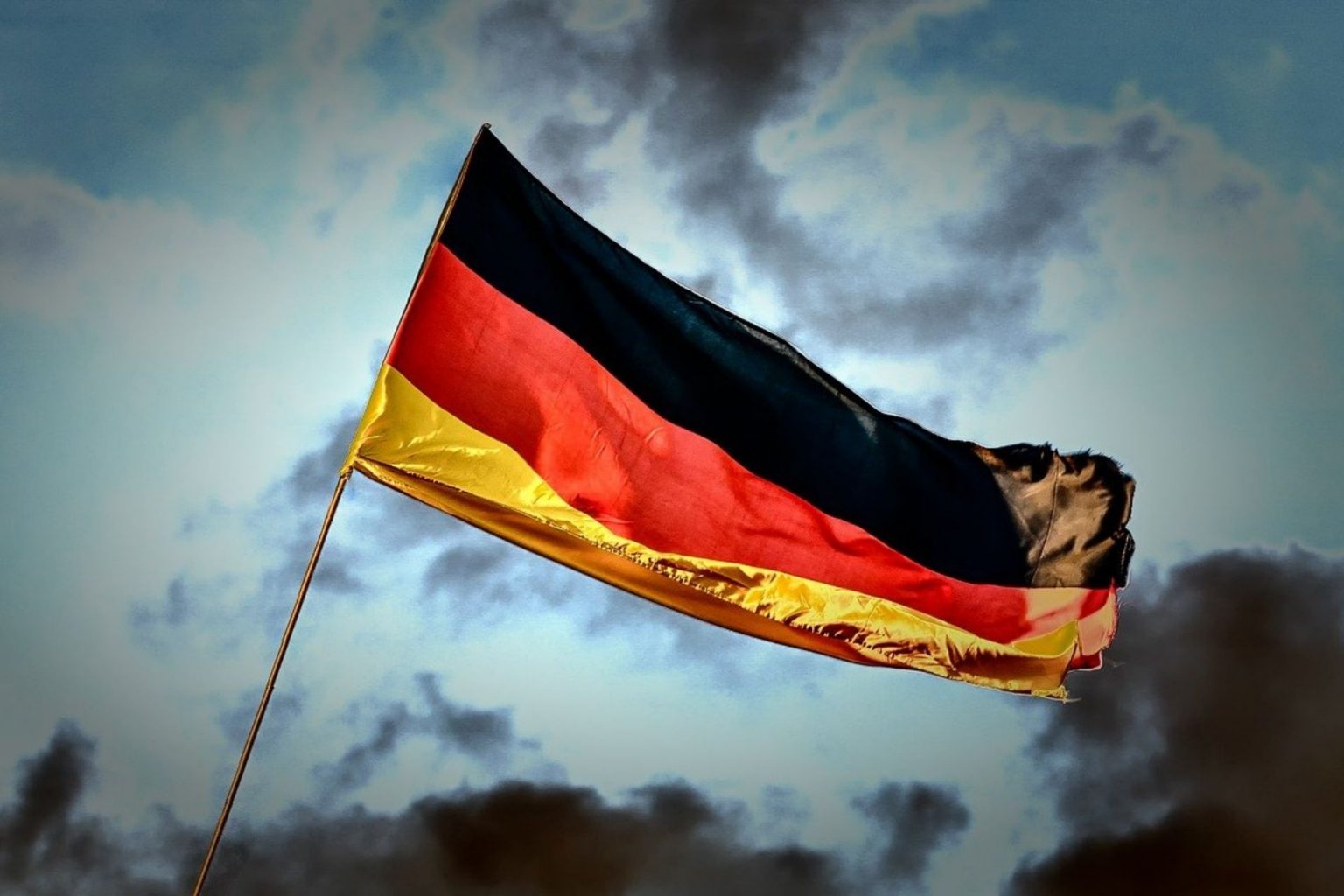 A German flag against a dark night sky and clouds