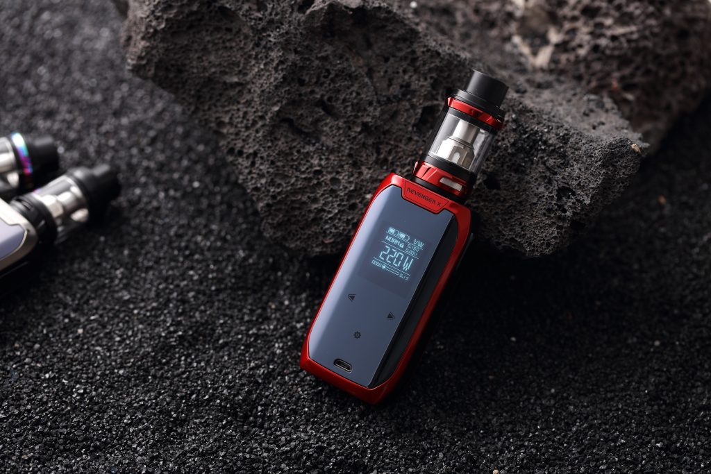 a red vaporesso vape mod sat next to a black rock