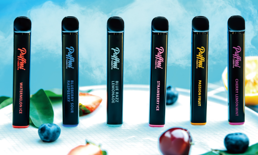 puffmi tx600 pro new vape disposable range - 6 pen sized black disposable ecigarettes sit infront of a blue background surrounded by fruit