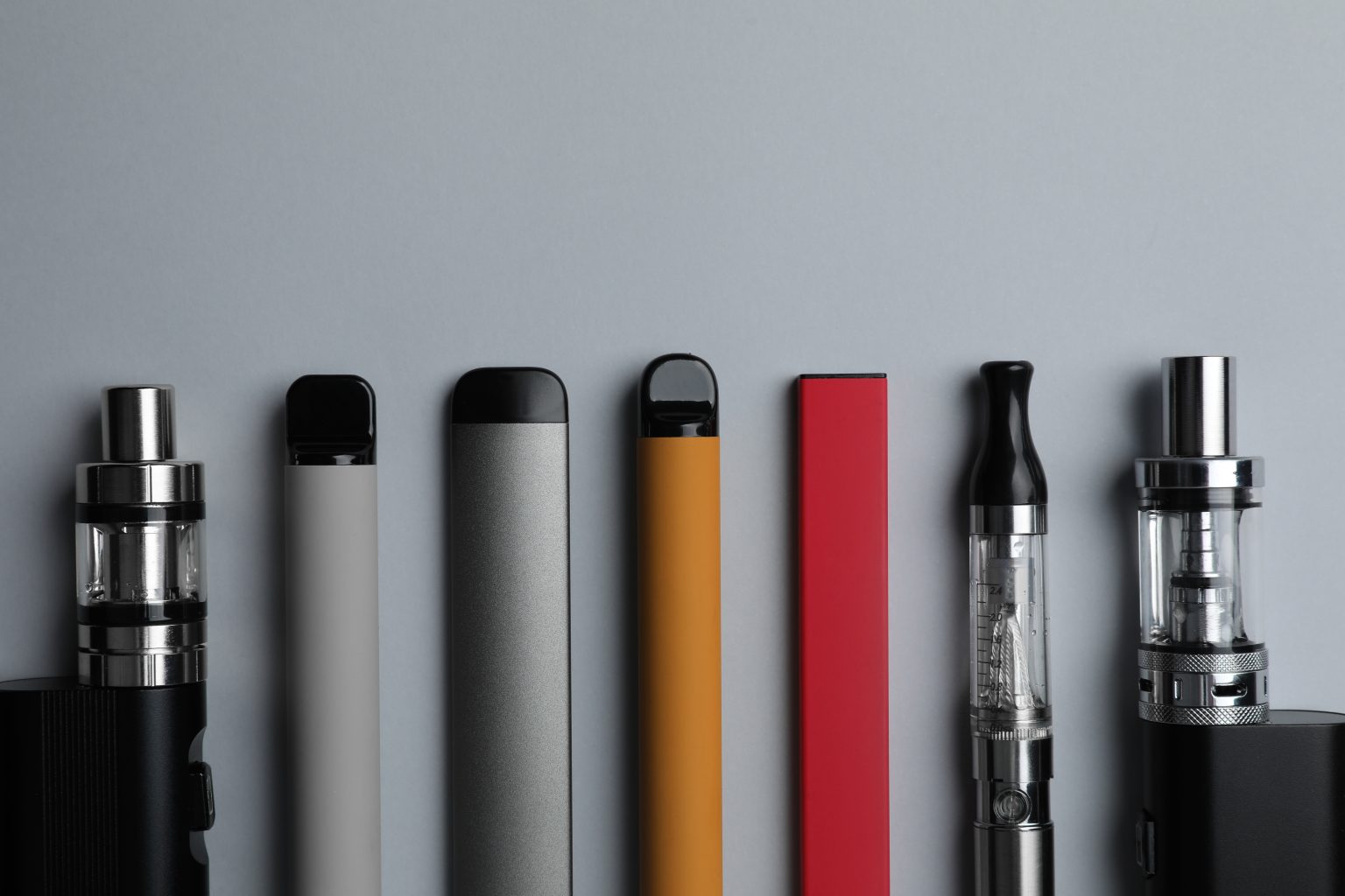 variety of electronic cigarettes on light grey background