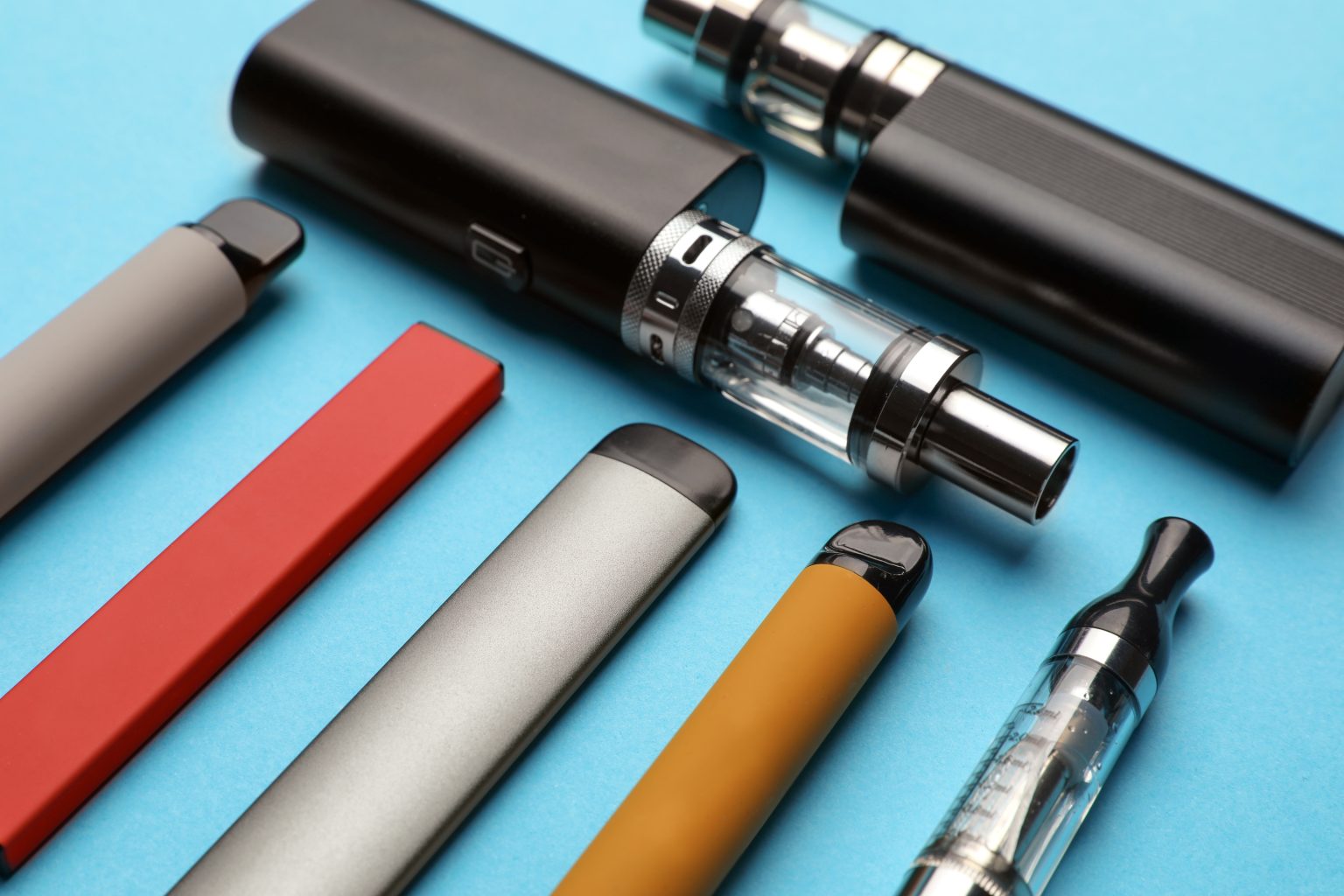 Different electronic cigarettes on light blue background