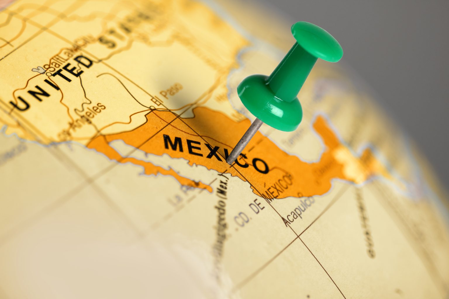 Green pin on a globe map, pointing to mexico