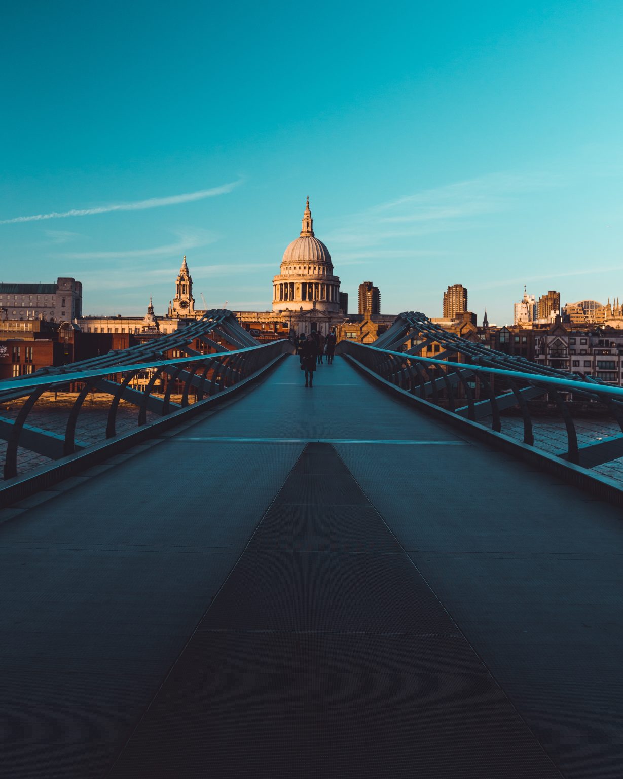 Millennium Bridge St Paul's Cathedral on modern London city skyline with blue sky