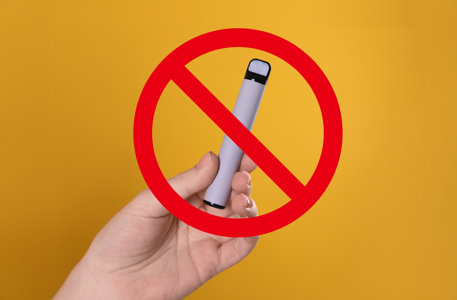 hand holding a disposable vape in front of a yellow background with a red no sign