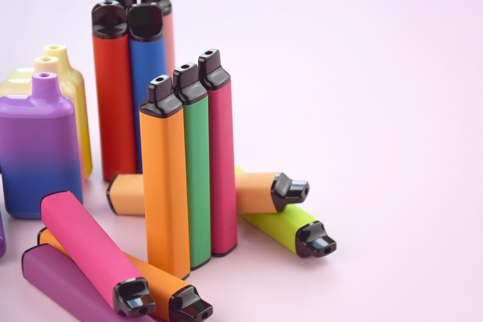 multicolor disposable single use vapes, electronic cigarettes on a pink background