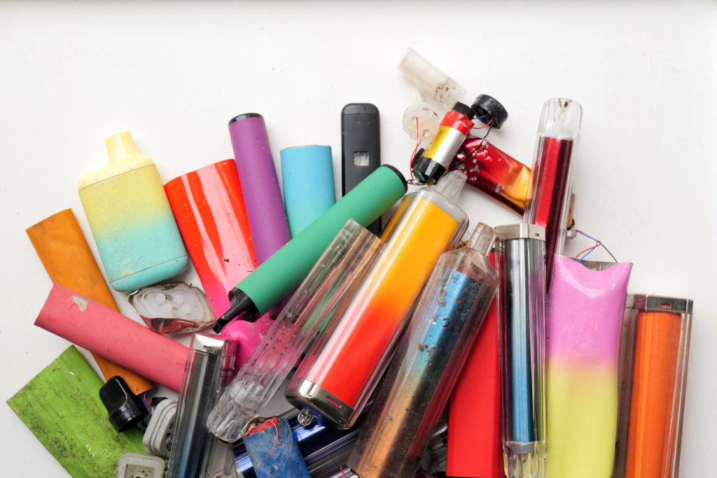 pile of multicoloured, single use, disposable vape devices. Batteries pulled out of disposable e-cigarette plastic casings