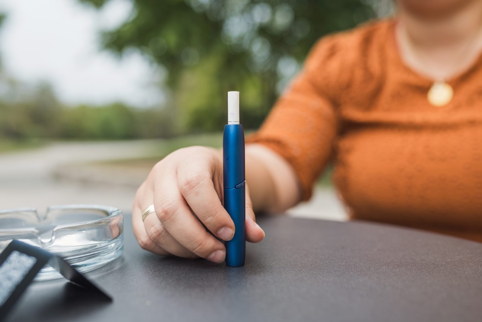 women sat outside enjoying a break with a heated tobacco device